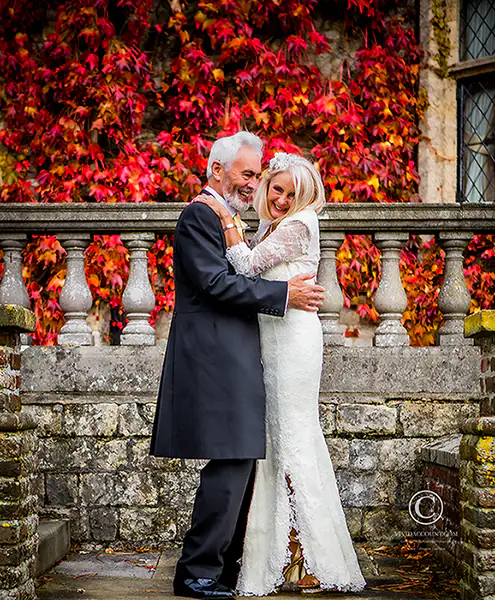 wedding portrait in private estate near tunbridge wells with bride and groom cuddling in front of rich red and yellow autumn foliage