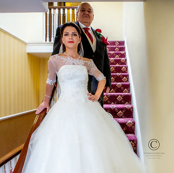 Bride poses with father of the bride on the staris at their Tunbridge Wells wedding venue, the Spa Hotel ahead of the wedding ceremony