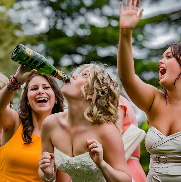 brides celebrates wedding reception with a bottle of champagne