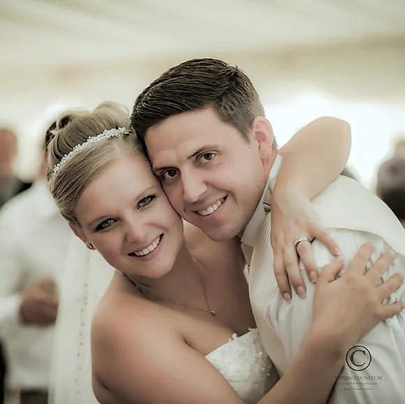 bride grabs her young groom during the wedding reception for a quick hug in front of the camera