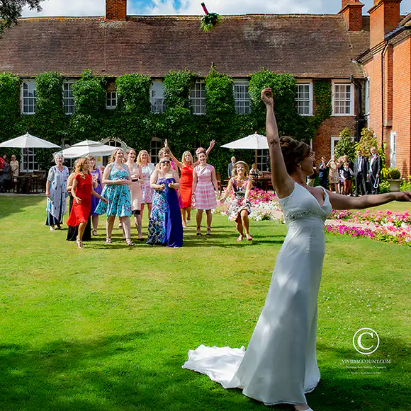 Bride throws wedding bouquet in the summer garden of her wedding venue near Tunbridge Wells