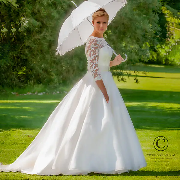 bride with wedding parasol walking through grounds of Salomons Estate in summer sun