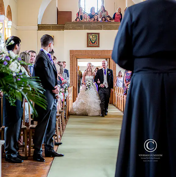 Father of the bride escorts his daughter inside the church to begin the wedding service