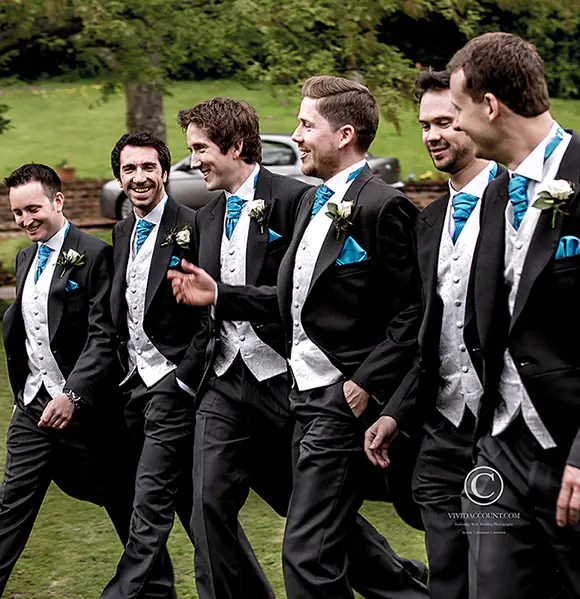 Groomsmen walking to Powdermills wedding venue in matching morning suits and talking animatedly