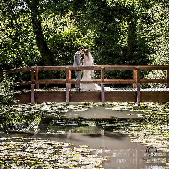 Bride and standing on the bridge over the lilly pond at Salomons Estate, Tunbridge Wells, Kent. Stealing a quiet moment alone together to enjoy the beautiful scenery at their wedding venue