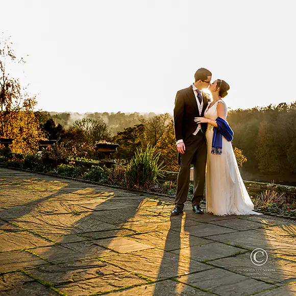 Sunset portrait of bride and groom on the terrace at Salomon's Estate with the Tunbridge Wells countryside shrouded in a little mist in the background
