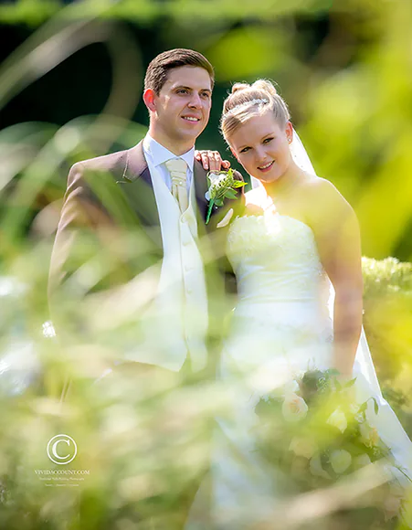 Bride and groom pose in a Tunbridge Wells summer meadow surrounded by medow flowers and long grass for a romantic wedding portrait
