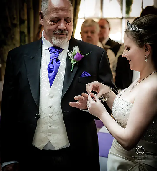 bride places wedding ring on grooms finger during their wedding ceremony in a Tunbridge Wells hotel