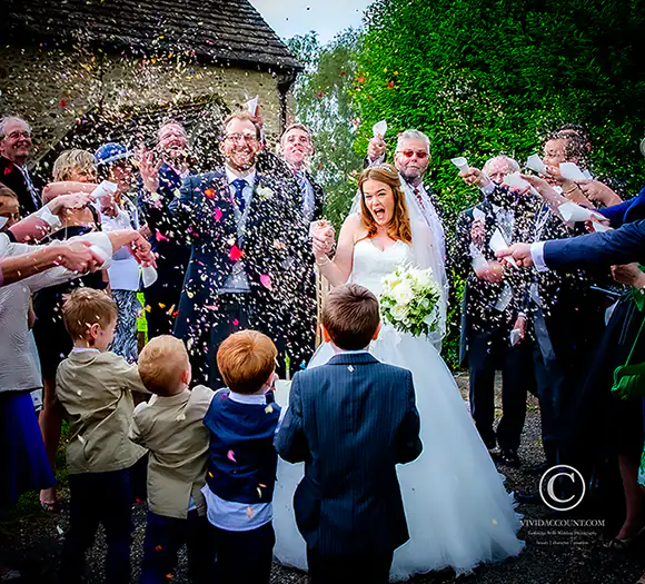 Bride and groom surrounded by wedding guests outside a Tunbridge Wells church and are showered in multi-coloured tunbridge wells wedding confetti