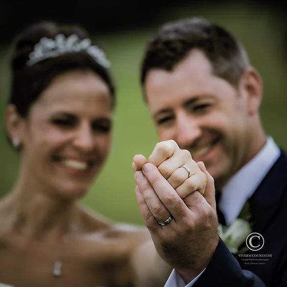 focusing on his and hers bespoke wedding rings by a Tunbridge Wells wedding jewellery designer with bride and groom out of focus in the background