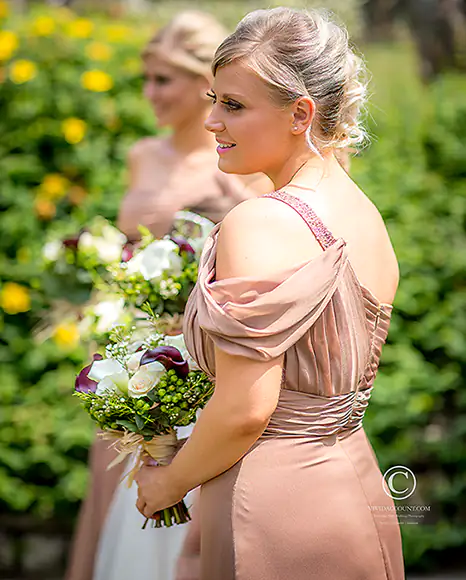 Bridesmaids in stylish venetian dresses await the bride  in warm Tunbridge Wells sunshine holding their purple wedding bouquets