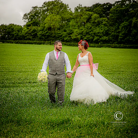walking hand in hand bride and groom laugh together in barley field near Tunbridge Wells