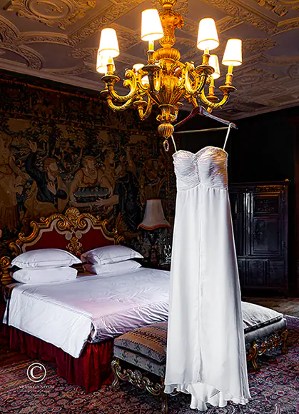 Elegant wedding dress hanging from golden chandelier in the bridal suite of an exclusive wedding venue near Tunbridge Wells, Kent