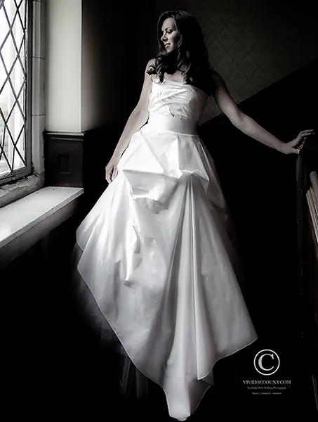 Bride poses in asymetric wedding dress on Stairs at Ashdown Park Hotel near Tunbridge Wells