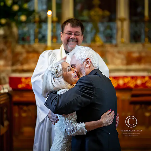A very warm affectionate hug after bride and groom exchange their wedding vows in church in front of the vicar at the altar
