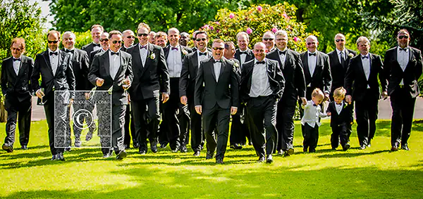 Bride, groom, groomsmen and ushers heading together acroos grounds of one warwick place, tunbridge wells to the wedding reception.