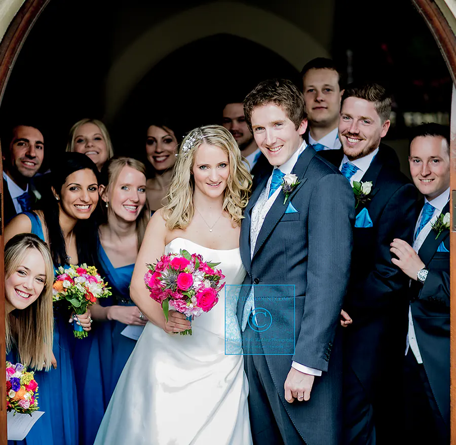 An informal, impromptu group wedding portrait of the bride, groom, bridesmaids and groomsmen as the wedding party leaves the church in Tunbridge Wells, Kent